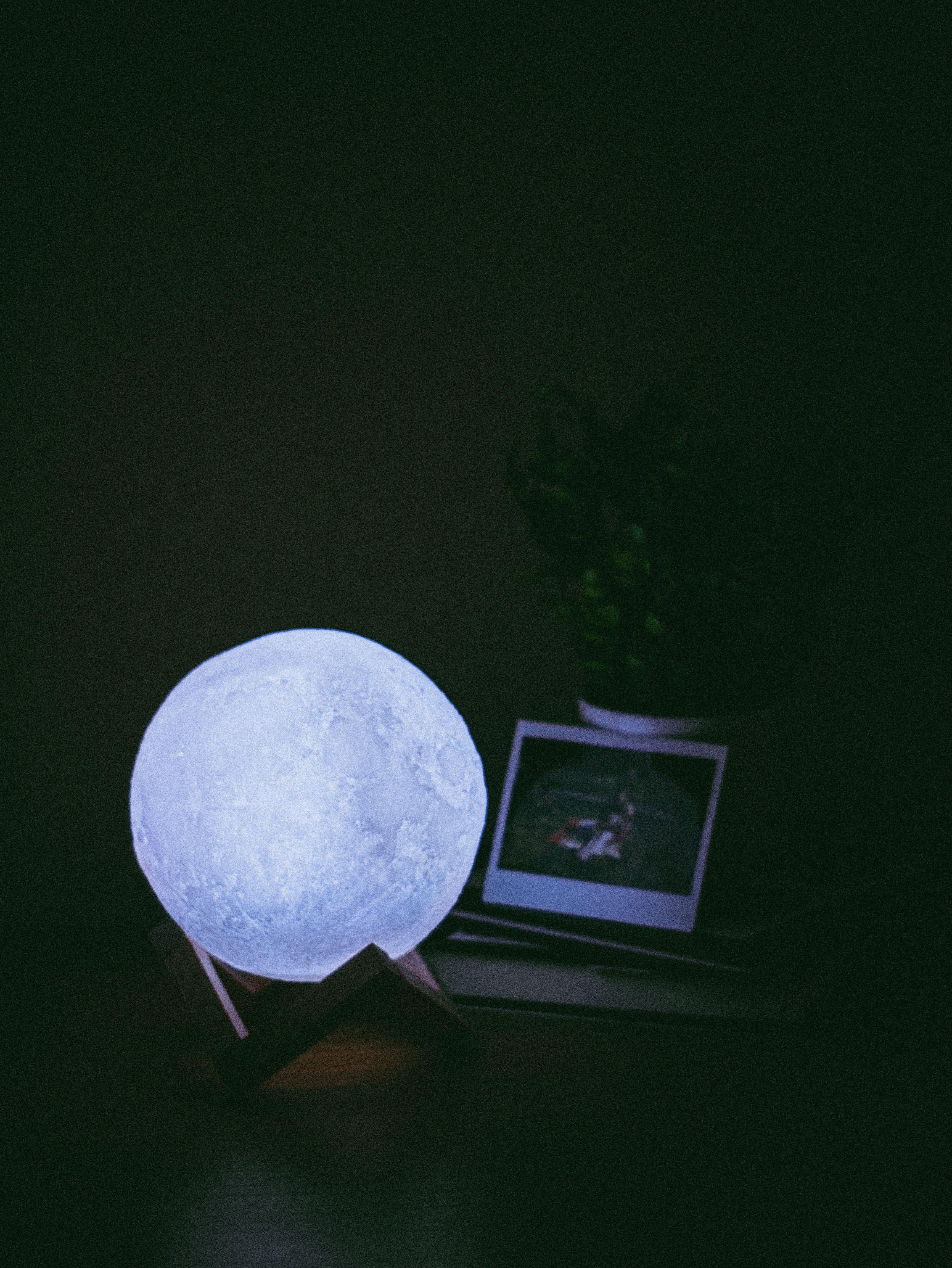 Moon-shaped lamp glowing on a small wooden stand in a dark room